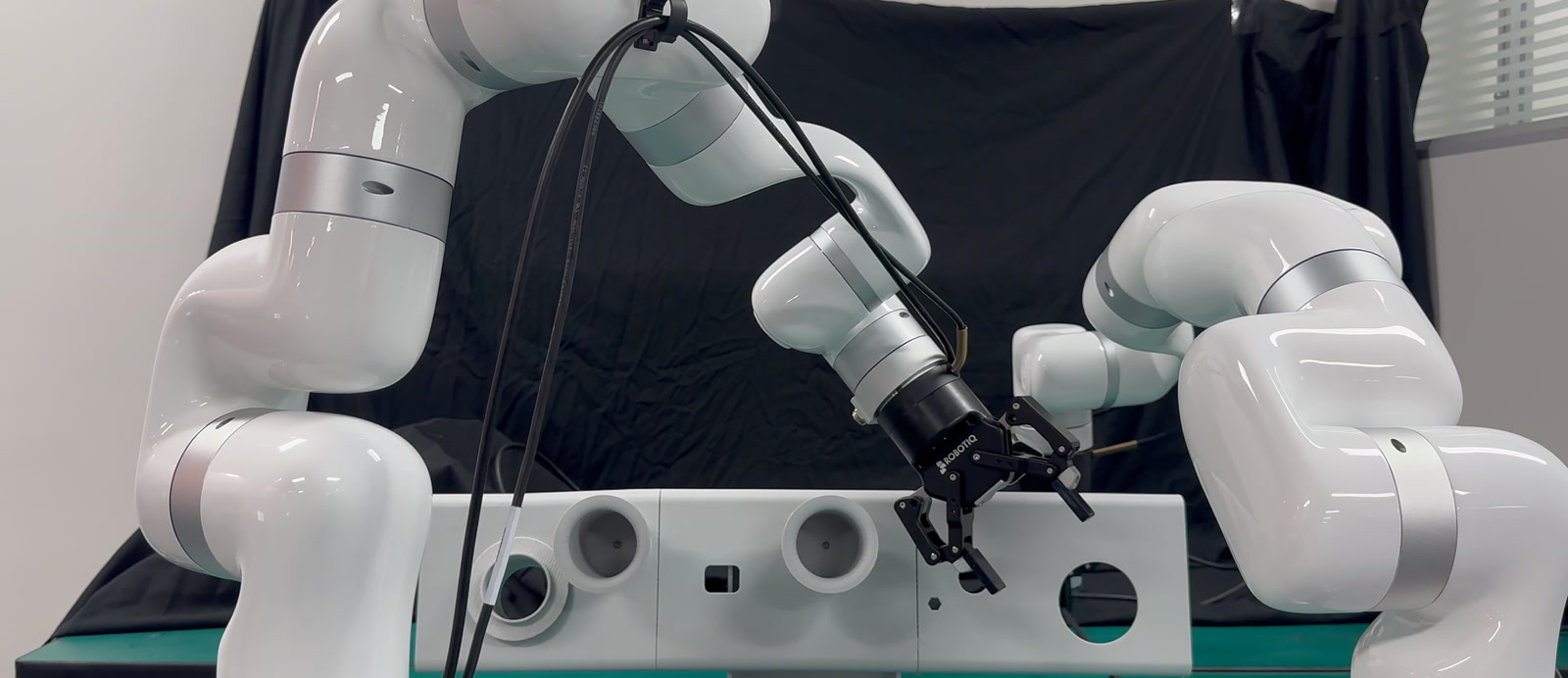 Two robot arms threading a wire harness